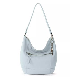 Light blue leather hobo bag with a shoulder strap, front zip pocket, and decorative chain with attached charms.