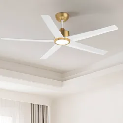 A modern ceiling fan with a gold and white finish, featuring five blades and an integrated light fixture, installed in a well-lit room with a tray ceiling and curtains.