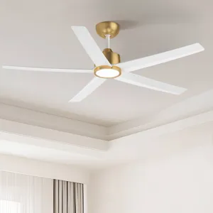 A modern ceiling fan with a gold and white finish, featuring five blades and an integrated light fixture, installed in a well-lit room with a tray ceiling and curtains.