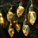 String lights featuring bulb-shaped ornaments with miniature snow scenes inside, including tiny trees and candy canes, illuminated with soft, warm lighting.