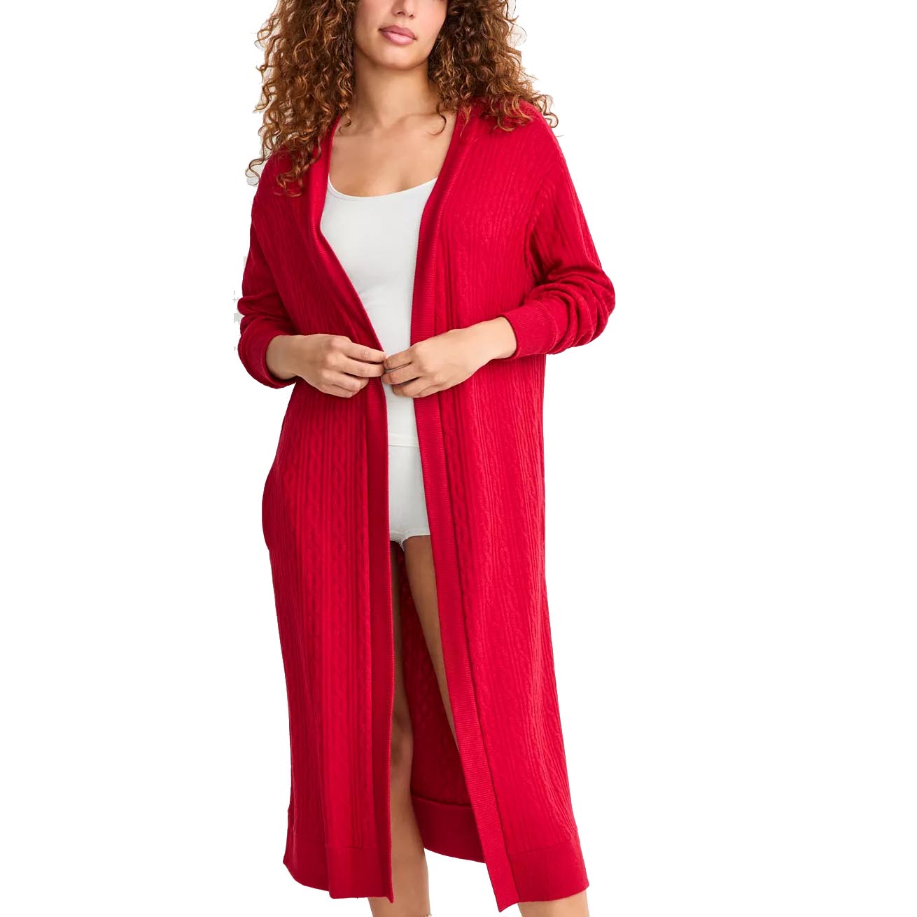 A woman is wearing a long, red knit cardigan over a white outfit. The cardigan features a cable knit pattern and has a relaxed, open-front design.