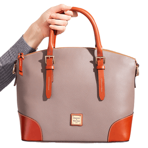 Dooney & Bourke Large Pebble Satchel in taupe pebbled leather with brown leather handles and trim, featuring gold-tone hardware and a logo plate on the front.