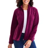 A woman is wearing a magenta fleece jacket with a full front zip and zippered pockets, paired with a white shirt and blue jeans.