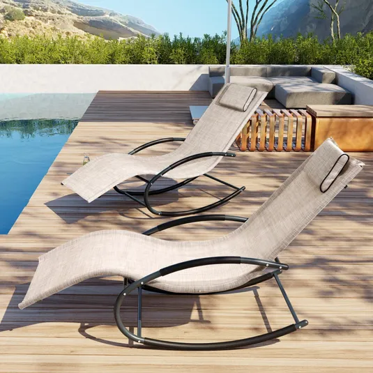Two modern outdoor sun loungers with curved black metal frames and beige mesh fabric sit poolside on a wooden deck, accompanied by a gray sectional sofa.