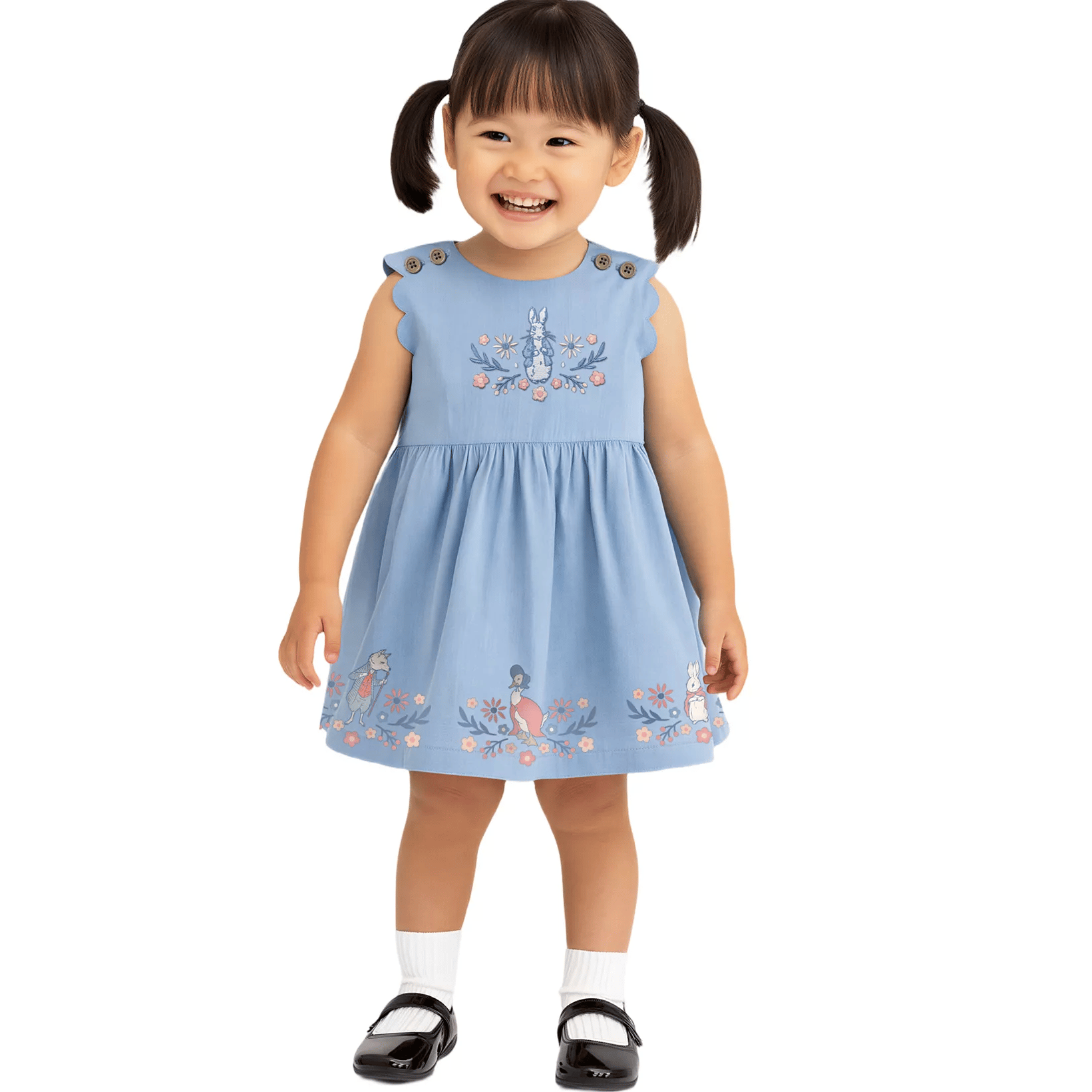A young girl wears a light blue sleeveless dress adorned with embroidered animals and floral designs, buttoned at the shoulders, paired with white socks and black shoes.