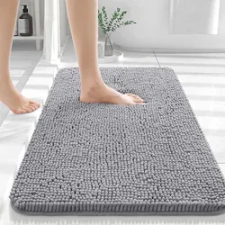 A gray chenille bath rug is displayed, featuring a thick, plush texture with an individual stepping onto it with bare feet.