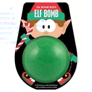 Da Bomb Elf Bath Bomb is a green bath fizzer with a Christmas cookie scent, featuring a holiday surprise inside. The packaging includes an illustration of an elf holding a candy cane.