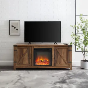 A wooden TV stand with a barn door design features a central electric fireplace insert, flanked by two cabinets with diagonal crossbar accents. It stands against a white brick wall and supports a flat-screen TV on top.