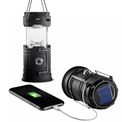 A black solar-powered lantern with a USB port for charging devices, shown hanging and lying on its side, with a smartphone connected and charging.