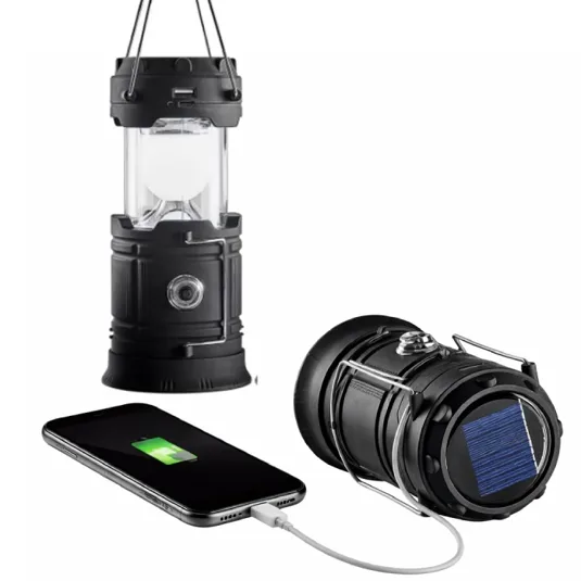 A black solar-powered lantern with a USB port for charging devices, shown hanging and lying on its side, with a smartphone connected and charging.