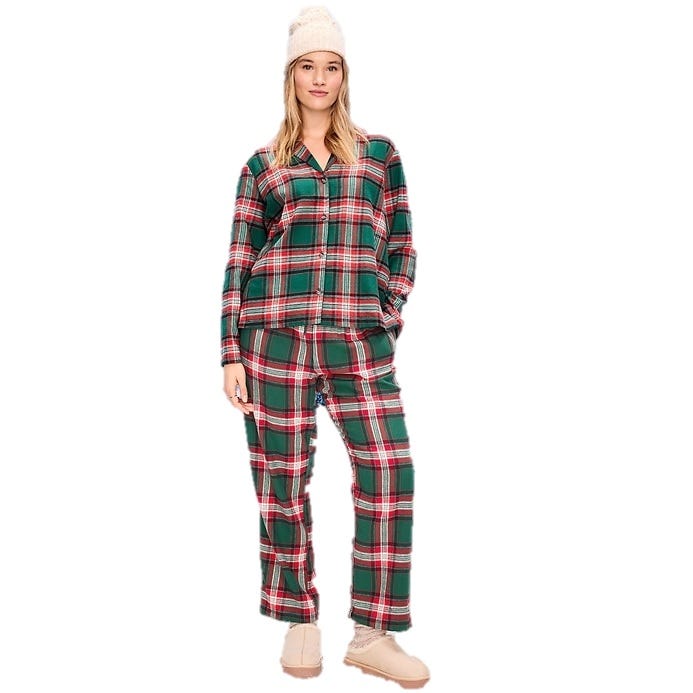 Woman wearing a green and red plaid pajama set with long sleeves and pants, accessorized with a beige knit beanie and tan slippers.