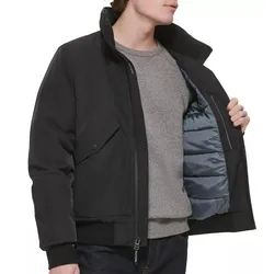 A man models a black jacket with a quilted inner lining, showcasing its insulation. He wears a gray sweater underneath, and the jacket features a flap pocket and zipper closure.