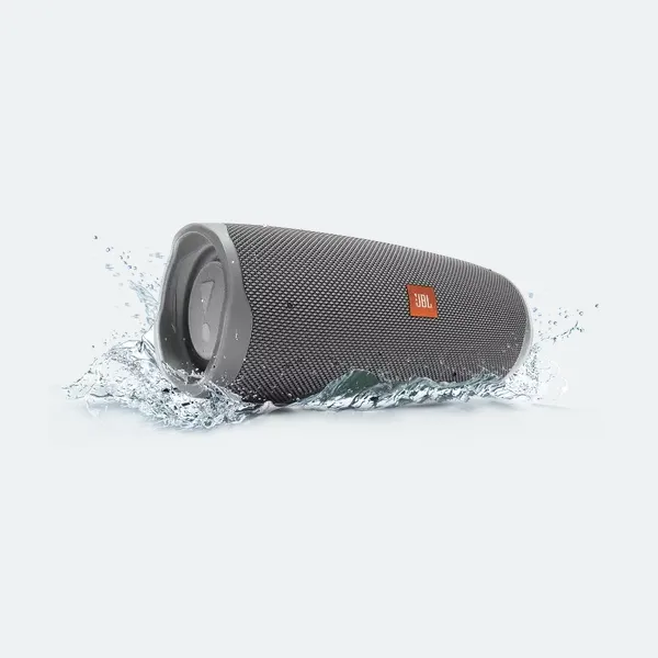 A gray portable Bluetooth speaker splashed with water, signifying water resistance.