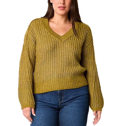 A woman in a mustard yellow, V-neck, textured knit sweater paired with blue jeans.