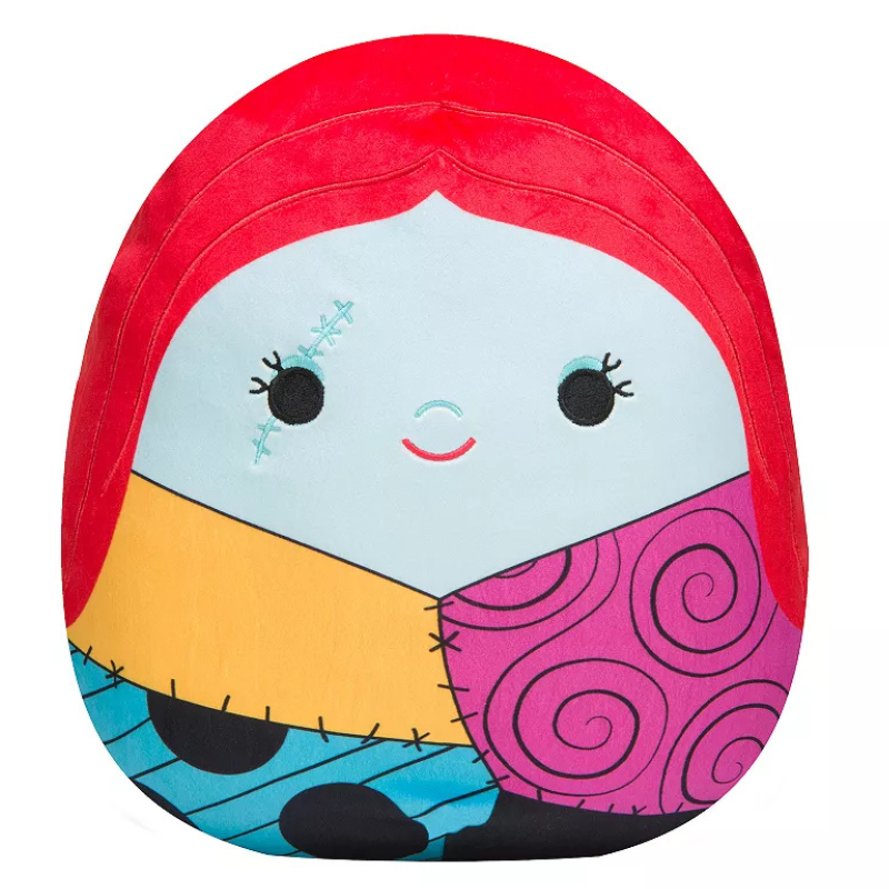 A plush pillow featuring a character with red hair, light blue face, and a patchwork-patterned dress with colorful swirls and stitches.