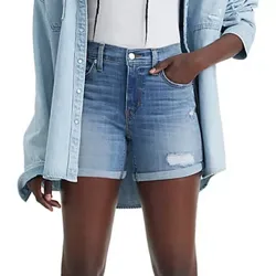 A person is wearing light-wash denim shorts with distressed details, paired with a light denim button-up shirt over a white top.