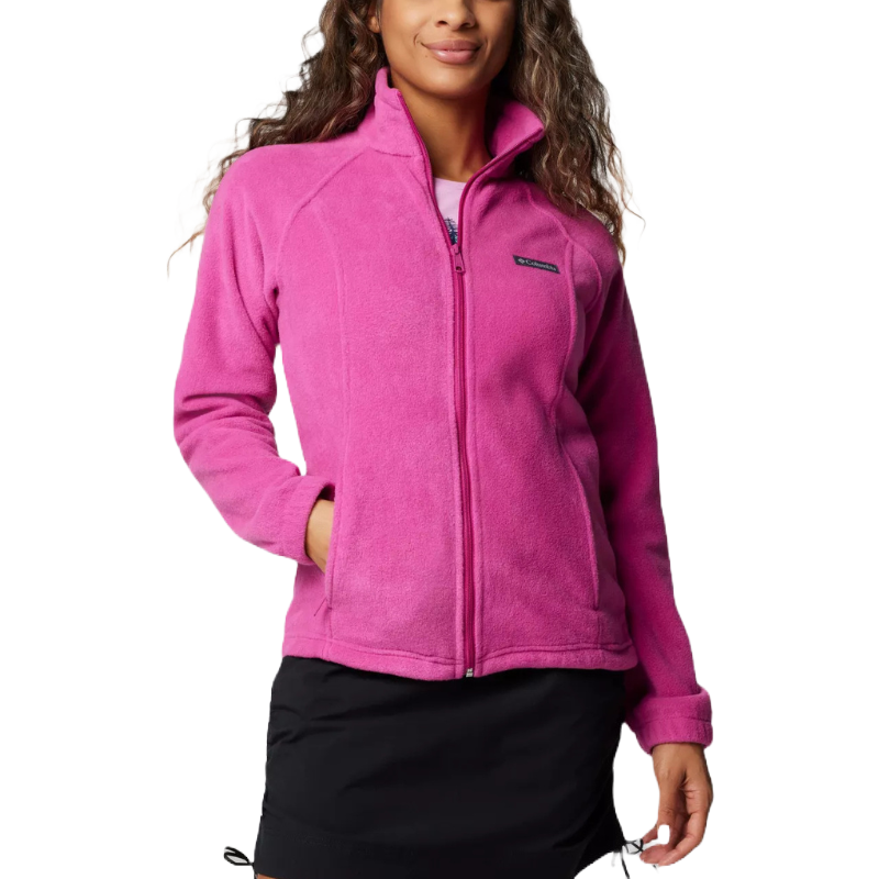 A woman is wearing a bright pink fleece jacket with a full zip, featuring a small logo on the left chest. She pairs it with a black skirt.