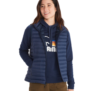 A woman is wearing a navy, quilted down vest over a navy hoodie with a mountain graphic, paired with brown pants.