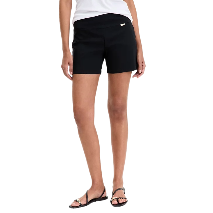 A woman is wearing black shorts paired with a white top and black sandals.