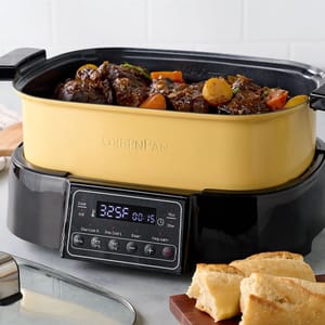 A yellow 8-in-1 GreenPan cooker with digital controls is shown, containing a stew with meat and vegetables, accompanied by slices of bread on a cutting board.