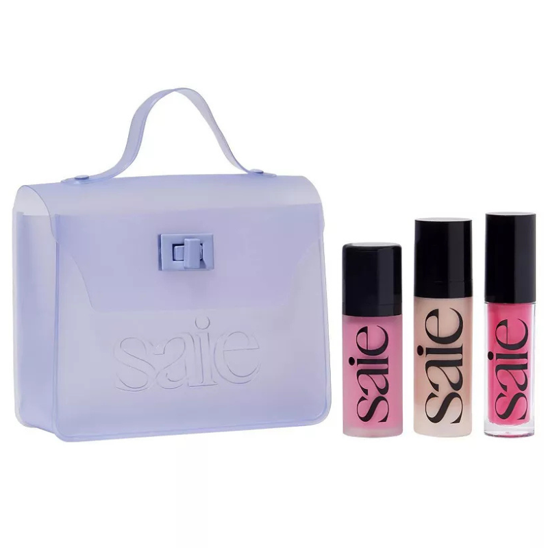 The 4pc Saie Essentials Starter Set includes three bottles of cosmetics in pink, beige, and pink shades and a translucent purple carrying case with a handle.