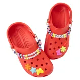 Pair of red clogs decorated with colorful charms and beads, featuring text like \“EXTRA VIBES\“ and \“FEELS IYKYK.\“