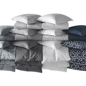 A stack of pillows and matching bedding in various shades of gray, blue, and white with geometric patterns.