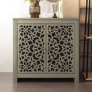 A decorative cabinet features intricate, floral cut-out designs on its doors, with a neutral color palette complemented by a modern vase, books, and reed diffuser on top.