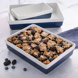 Set of blue and white ceramic baking dishes filled with a mixed berry crumble, featuring blackberries and blueberries.
