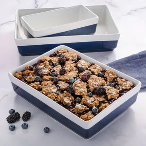 Set of blue and white ceramic baking dishes filled with a mixed berry crumble, featuring blackberries and blueberries.
