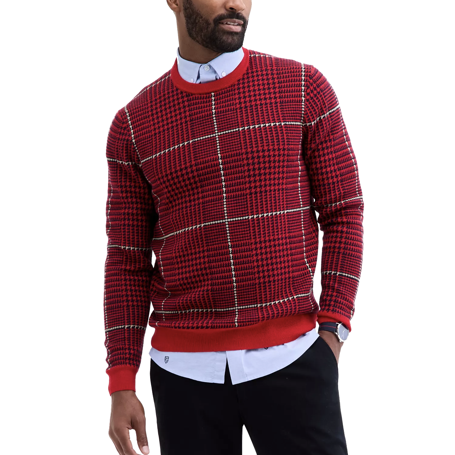 A man wears a red houndstooth-patterned sweater over a light blue dress shirt. The outfit is paired with black pants and a watch.