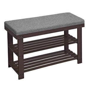 A dark brown wooden bench with a cushioned gray seat and two slatted tiers underneath for shoe storage.