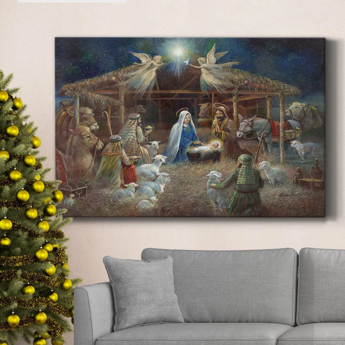 A Christmas-themed painting of the nativity scene is displayed above a gray sofa next to a decorated Christmas tree with gold ornaments.