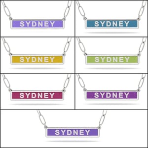 Seven necklaces with rectangular pendants featuring the name \“Sydney\“ in various colors: purple, blue, yellow, green, pink, and two shades of purple.