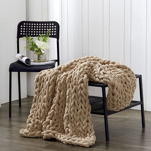 a chunky knit brown throw on a black table