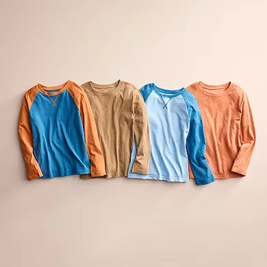 Four long-sleeve raglan tees in blue/orange, tan, light blue, and salmon, each with contrasting sleeves, are displayed side by side.