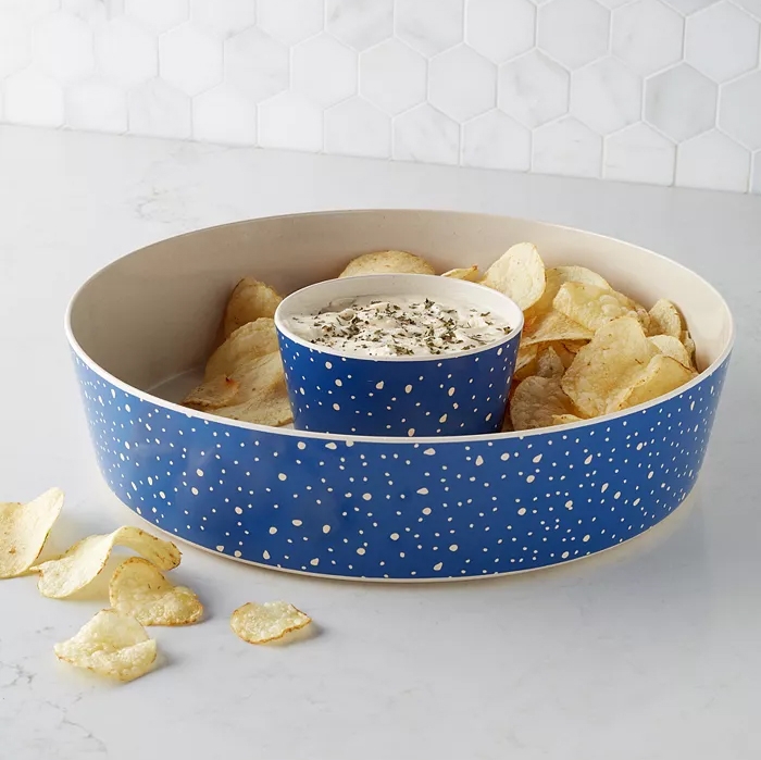 A chip and dip serving set with a blue polka-dotted dip bowl nested in a larger off-white snack bowl.