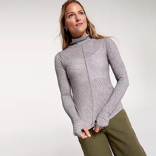 A woman is wearing a gray turtleneck with a textured pattern and olive green pants.