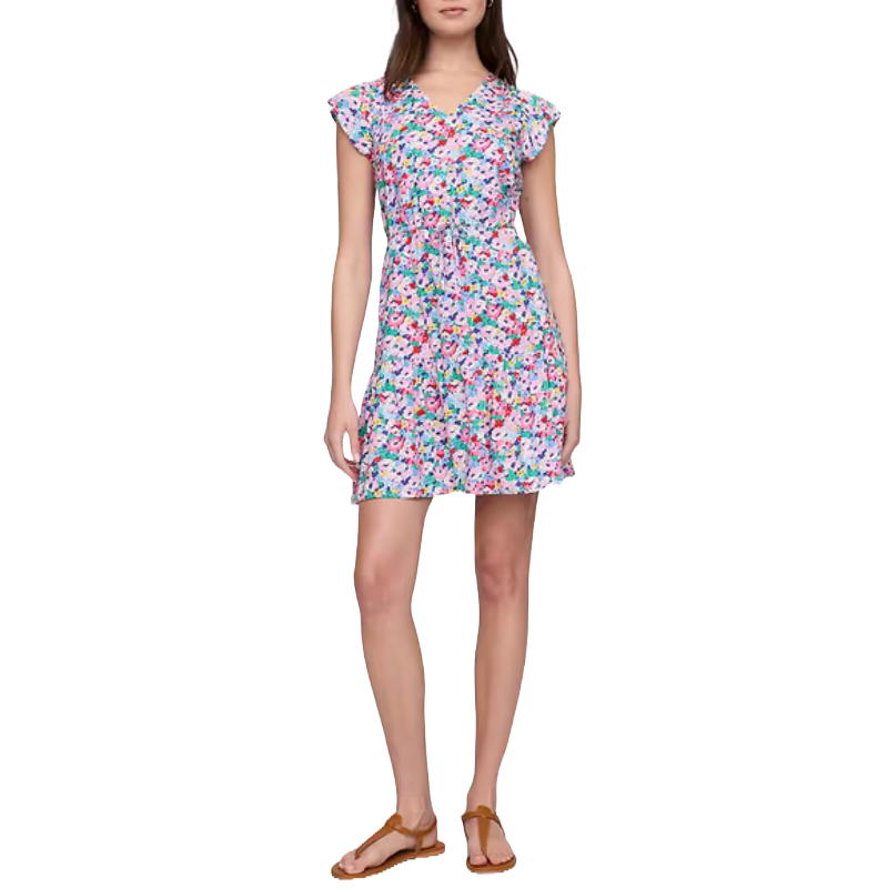 A woman is wearing a floral print dress with short flutter sleeves and a tie waist, paired with brown sandals.