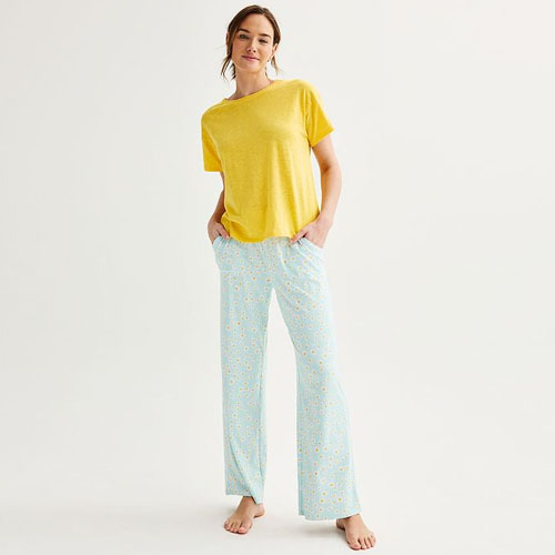 A woman wearing a yellow t-shirt and light blue patterned pajama pants.