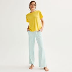 A woman wearing a yellow t-shirt and light blue patterned pajama pants.