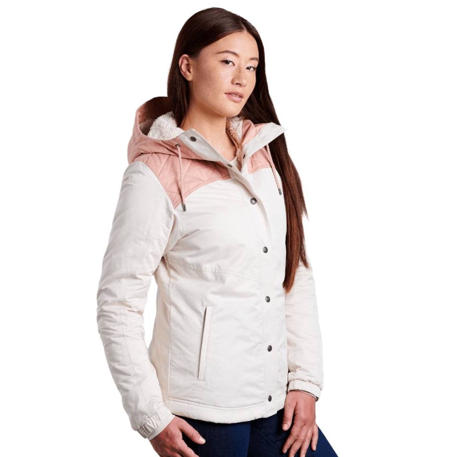 The Kuhl Hooded Jacket is white with a light pink accent on the shoulders and features a hood lined with soft fabric. It has a front zip and snap closure, two side pockets, and fitted cuffs.