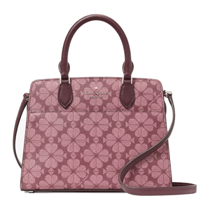 A small satchel by Kate Spade with a flower motif design in shades of pink and purple, featuring two handles, a detachable strap, and the brand's logo in gold lettering.
