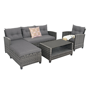 4-piece grey patio furniture set with wicker frame includes a sectional sofa with chaise, an armchair, a glass-top coffee table, and decorative cushions.