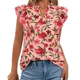 A woman wears a floral blouse with ruffled sleeves, featuring a pink background and red flowers, paired with blue jeans.