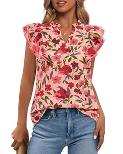 A woman wears a floral blouse with ruffled sleeves, featuring a pink background and red flowers, paired with blue jeans.