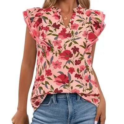 A woman wears a floral blouse with ruffled sleeves, featuring a pink background and red flowers, paired with blue jeans.