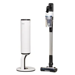 A Levoit cordless stick vacuum is shown next to its sleek, cylindrical charging and storage base.