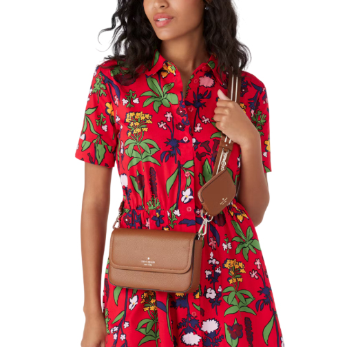 A brown Kate Spade crossbody bag with an attached small pouch, featuring a sleek design and gold brand detailing. It is worn over a red floral dress.