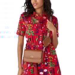 A brown Kate Spade crossbody bag with an attached small pouch, featuring a sleek design and gold brand detailing. It is worn over a red floral dress.